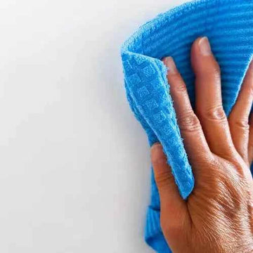 Mano limpiando una superficie con un paño sueco de color azul